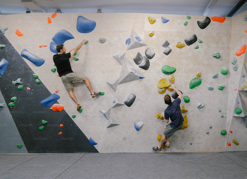 dois homens estão escalando em uma parede de rocha