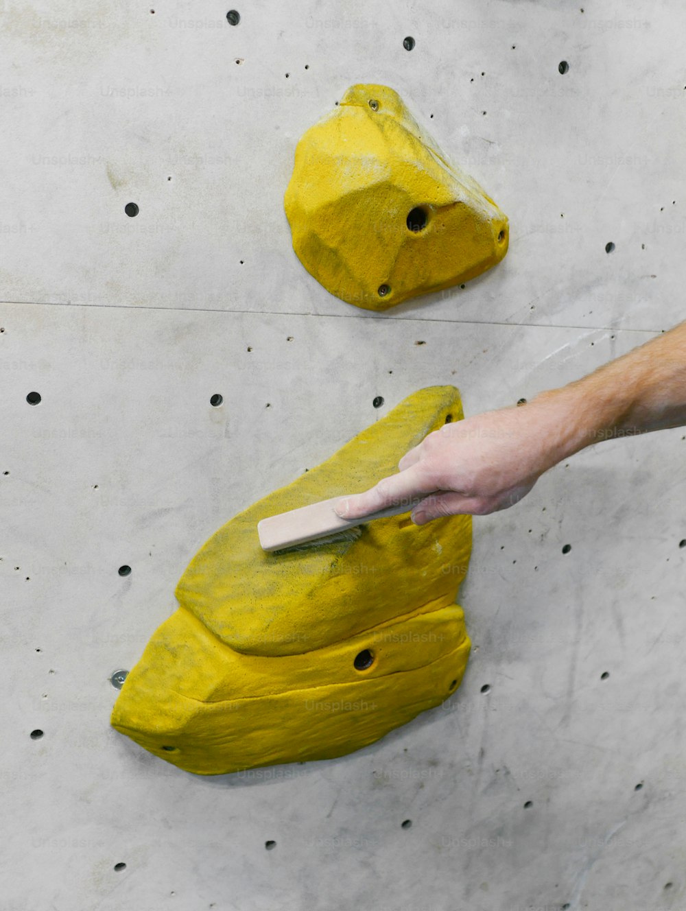 a person is painting a yellow object on a wall