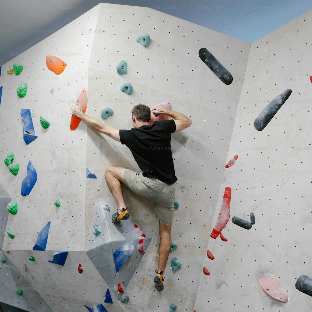 a man climbing up the side of a climbing wall