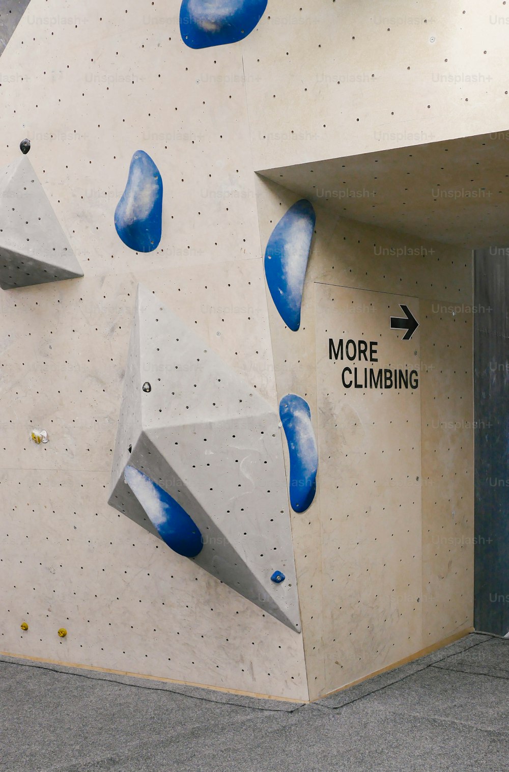 a climbing wall with a sign pointing to more climbing