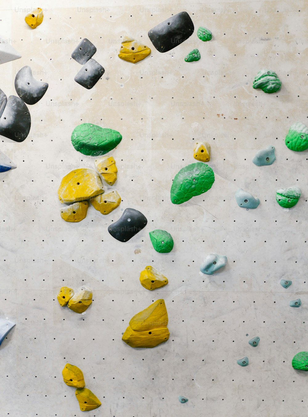 Una parete da arrampicata piena di tante rocce verdi e gialle