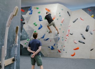 um homem em uma parede de escalada em um ginásio