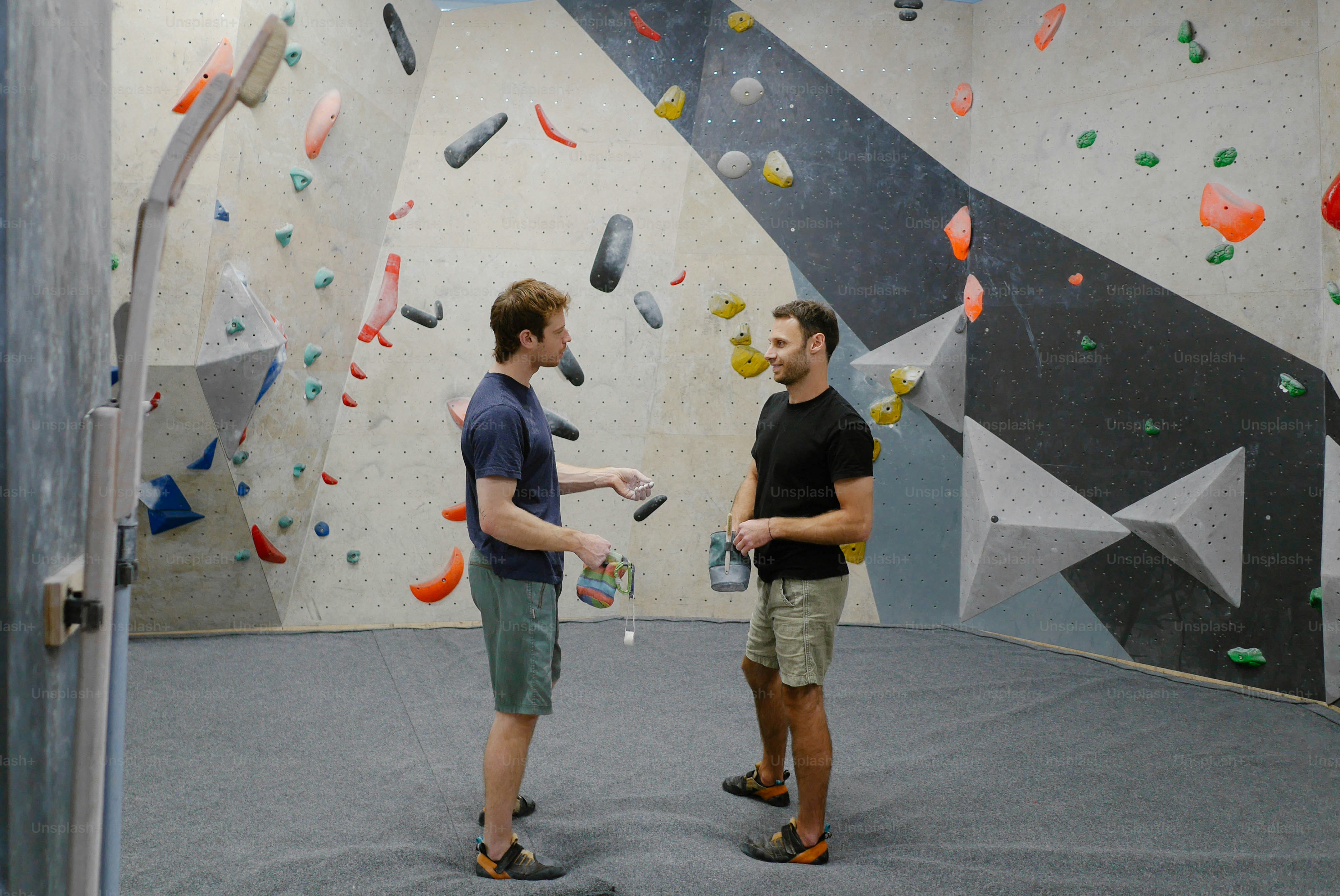 A couple of men standing in front of a climbing wall photo – Climbing ...
