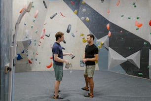 a couple of men standing in front of a climbing wall