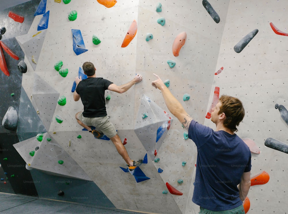 two men are climbing on a rock wall