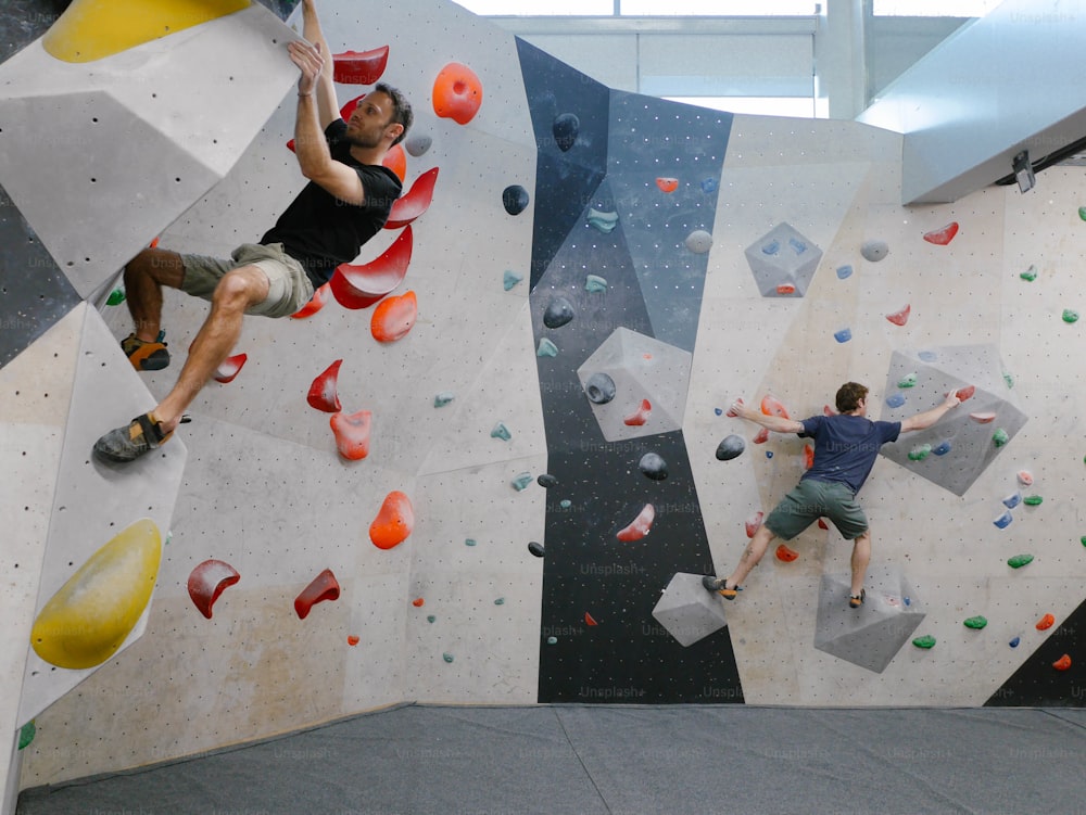 two men are climbing on a climbing wall