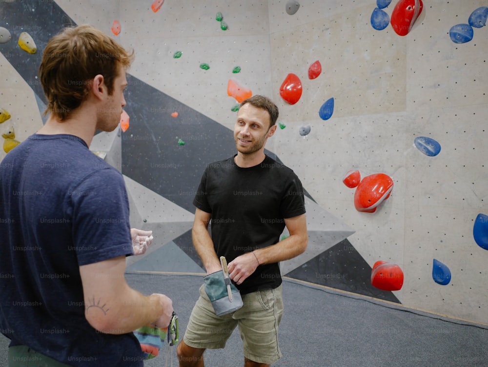 two men standing in front of a climbing wall