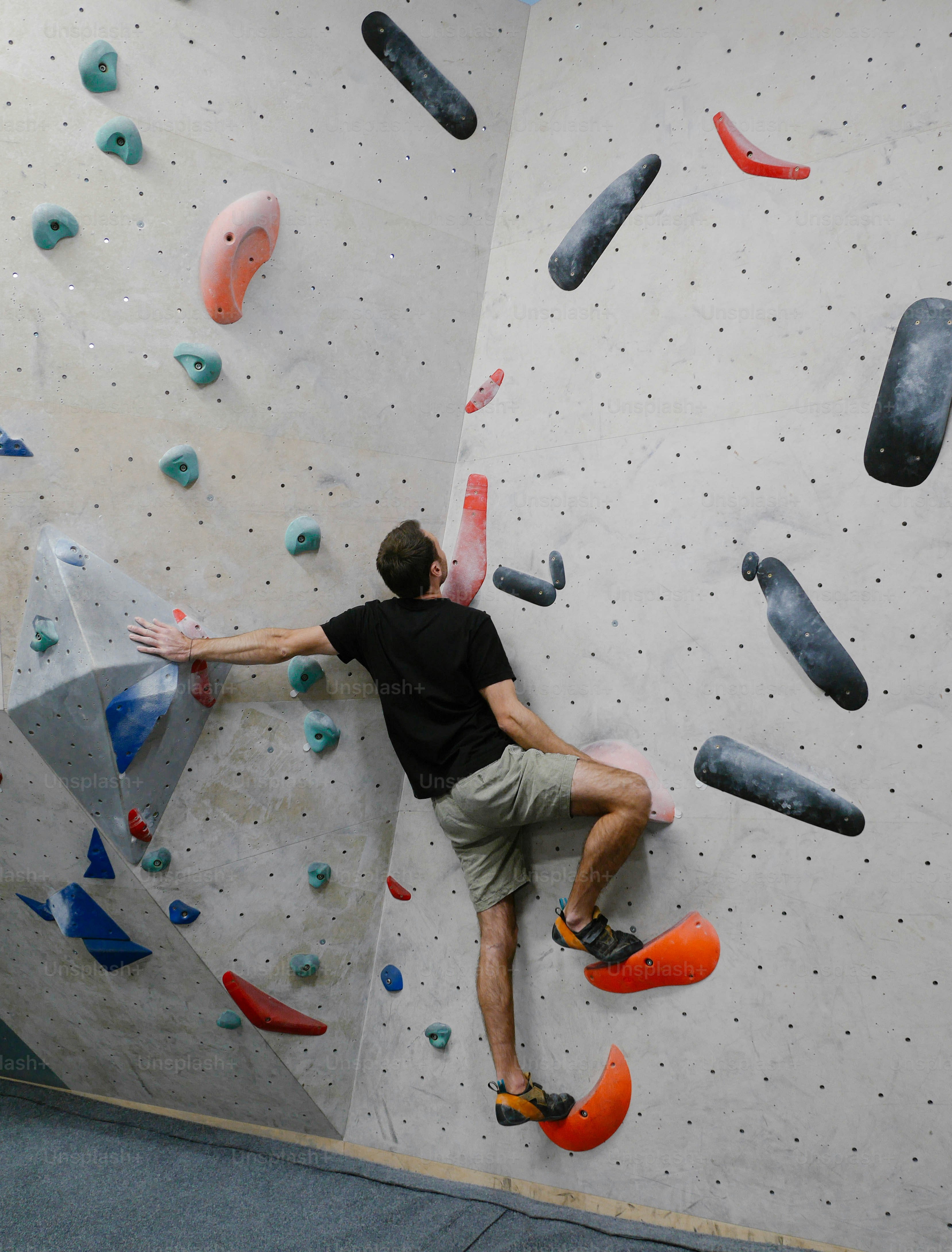 a man climbing up the side of a climbing wall