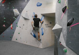 Ein Mann klettert an der Seite einer Kletterwand hinauf