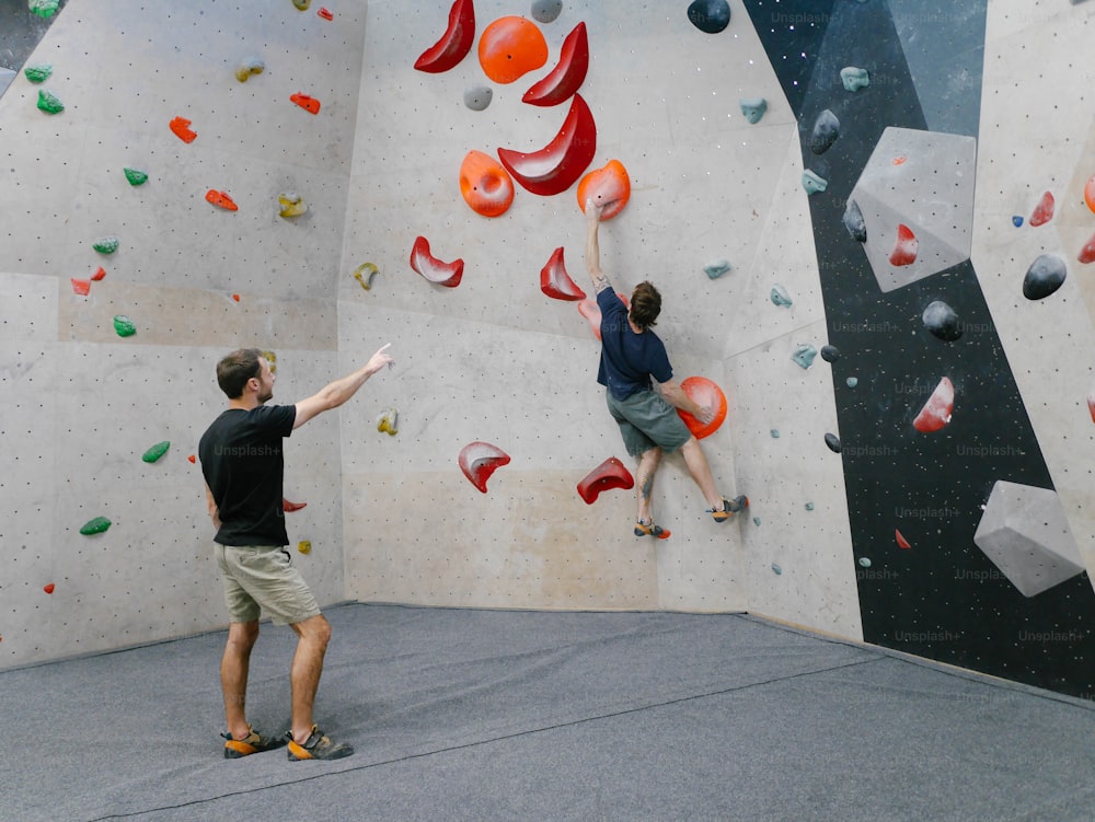 two men are climbing on a rock wall