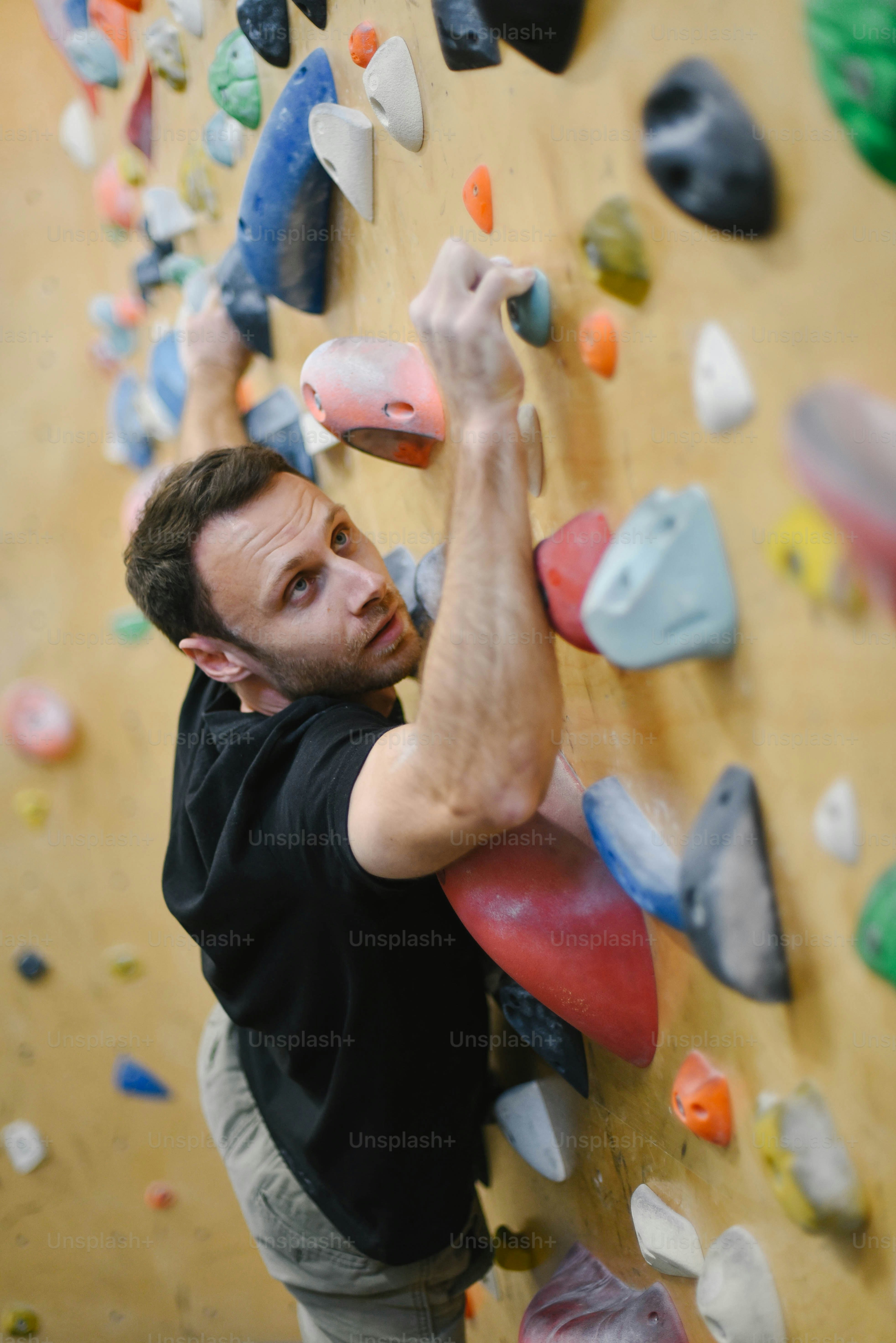 a man climbing up the side of a climbing wall
