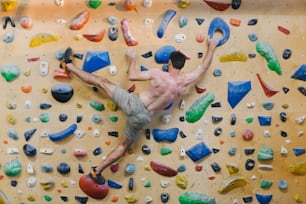 a shirtless man climbing on a climbing wall