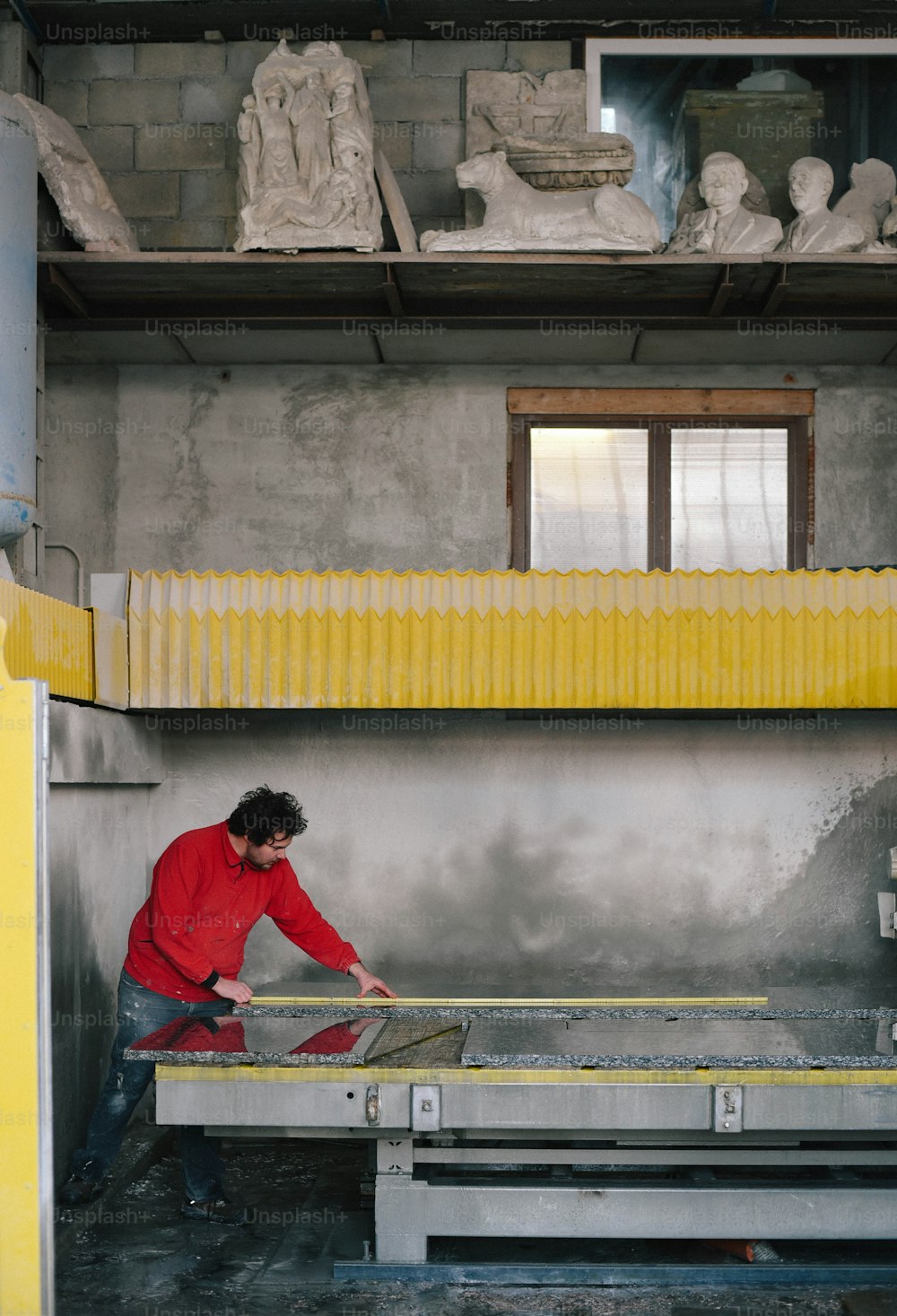 a man in a red shirt working on a sculpture