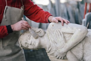 Un uomo sta lavorando su una statua di donna