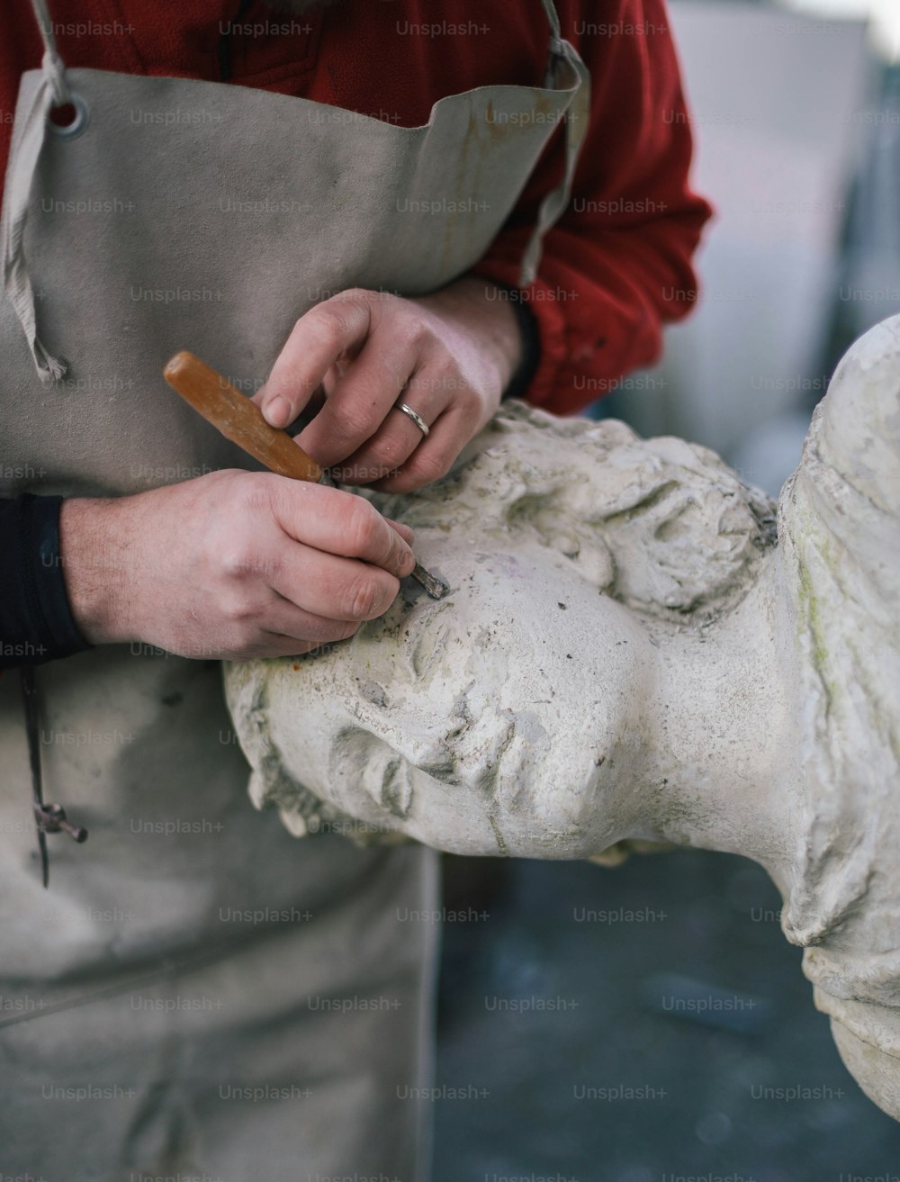 um homem está trabalhando em uma estátua com um pedaço de madeira