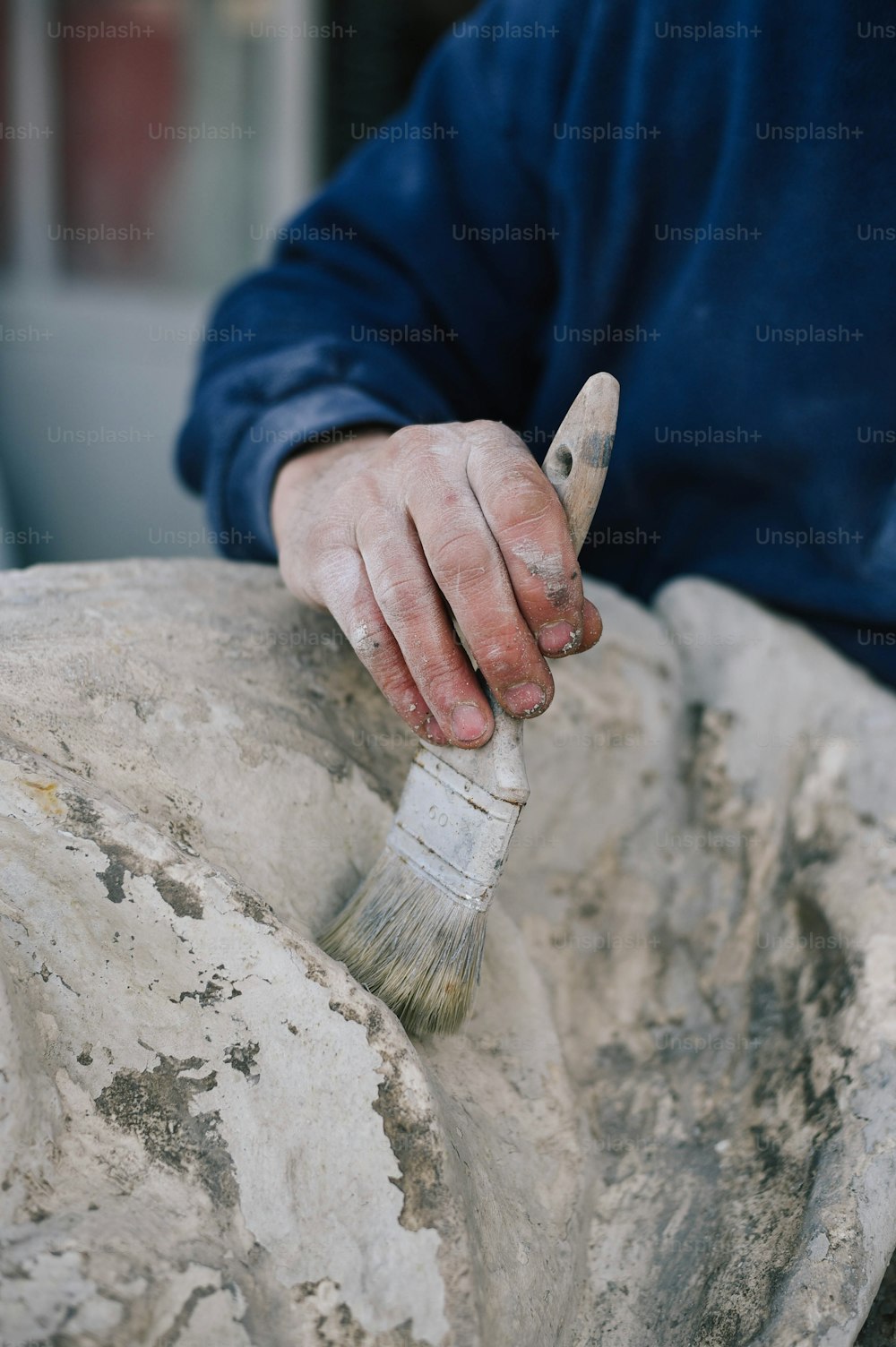 a person holding a paintbrush on top of a rock