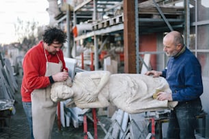 two men working on a sculpture in a factory