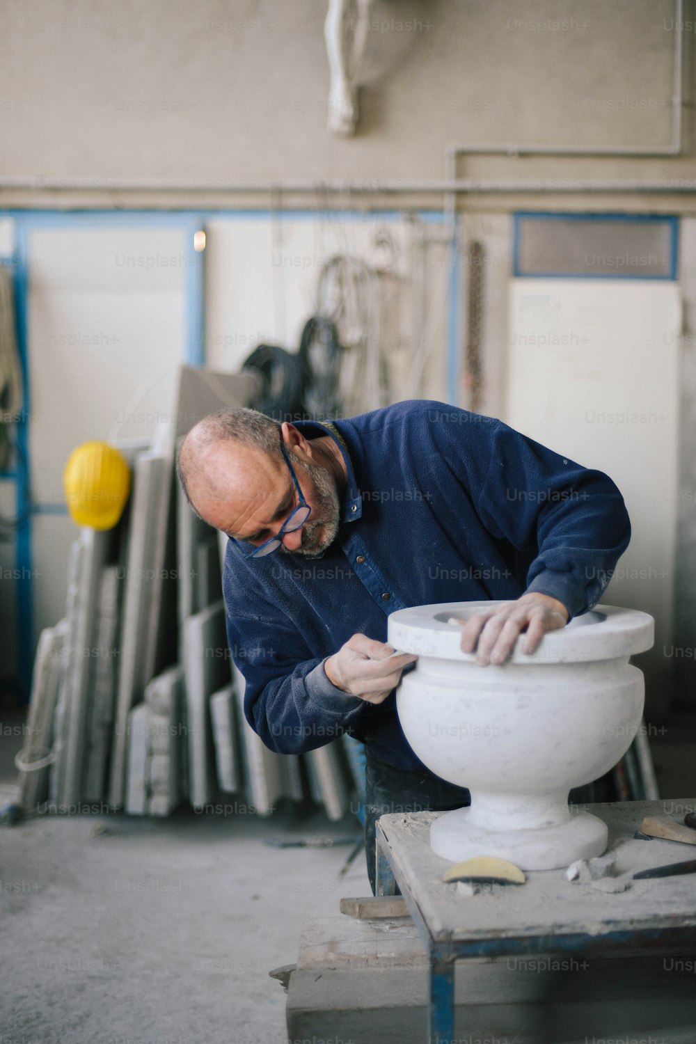 Un homme travaille sur un vase blanc