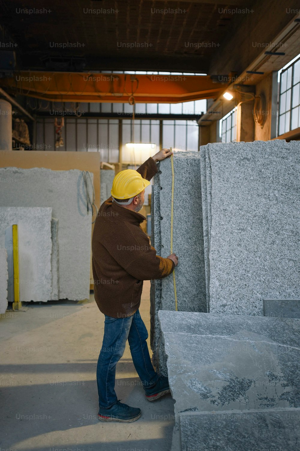 a man in a yellow hat is working on some granite
