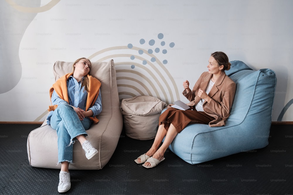 two women sitting on bean bags talking to each other