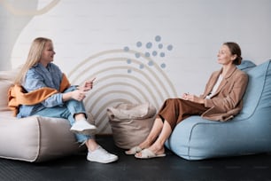 two women sitting on bean bags talking to each other