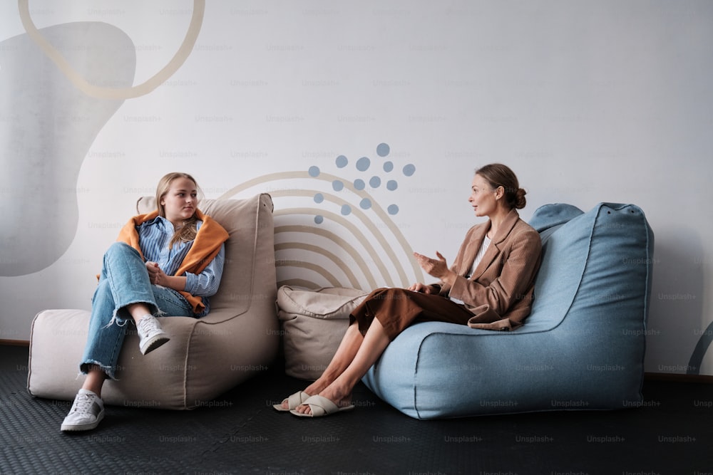 two women sitting on bean bags in a room