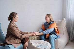Due donne sedute su un divano che stringono la mano