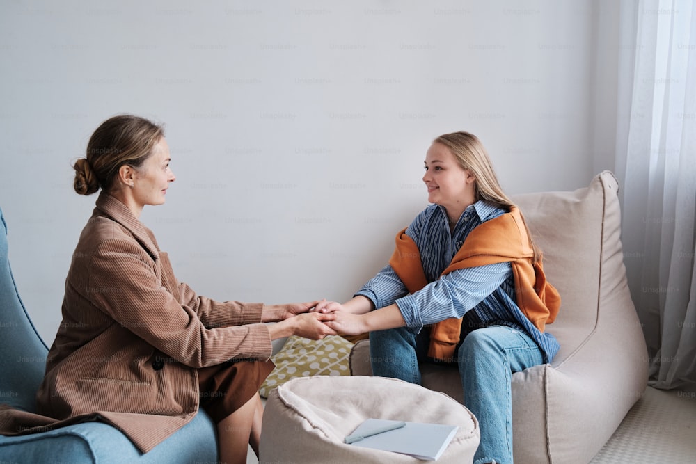 two women sitting on a couch shaking hands