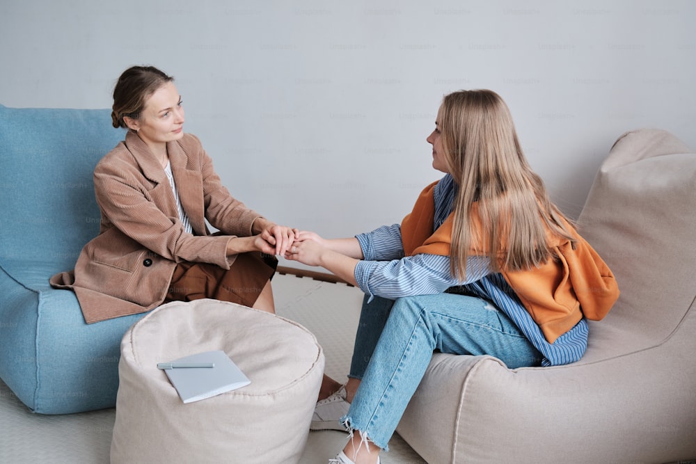 two women sitting on a couch shaking hands