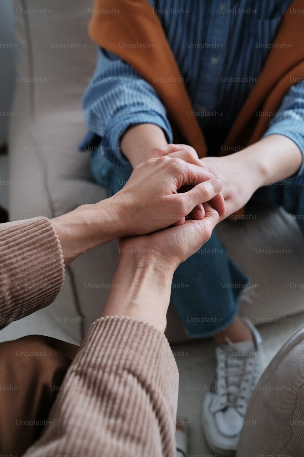 two people holding hands while sitting on a couch