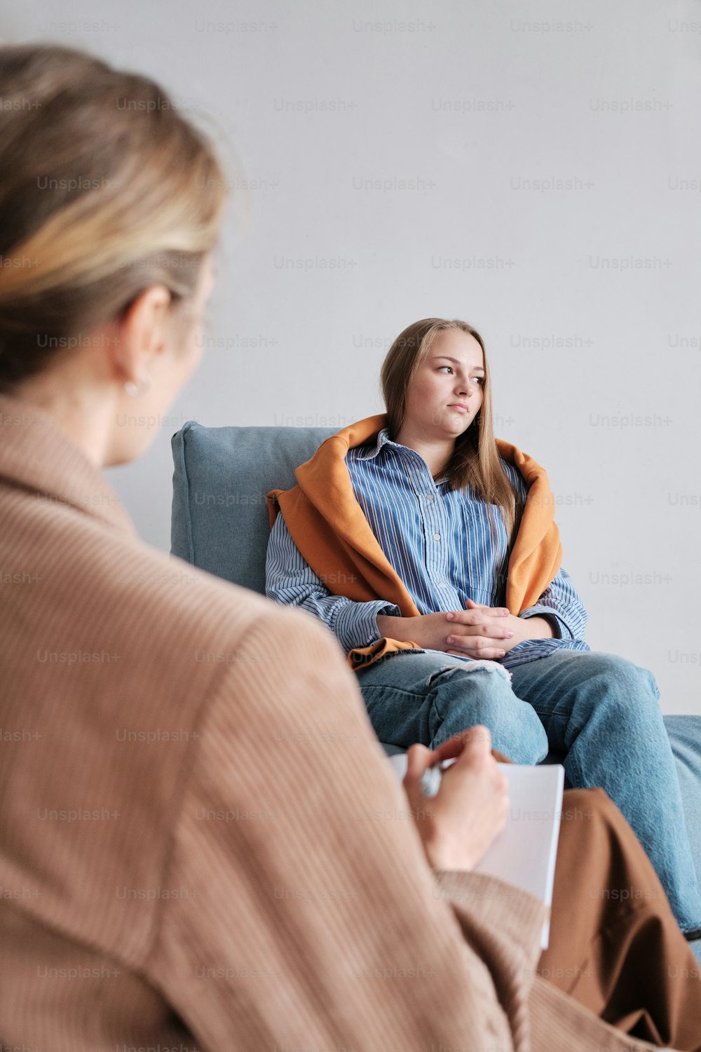 a woman sitting on a couch talking to another woman