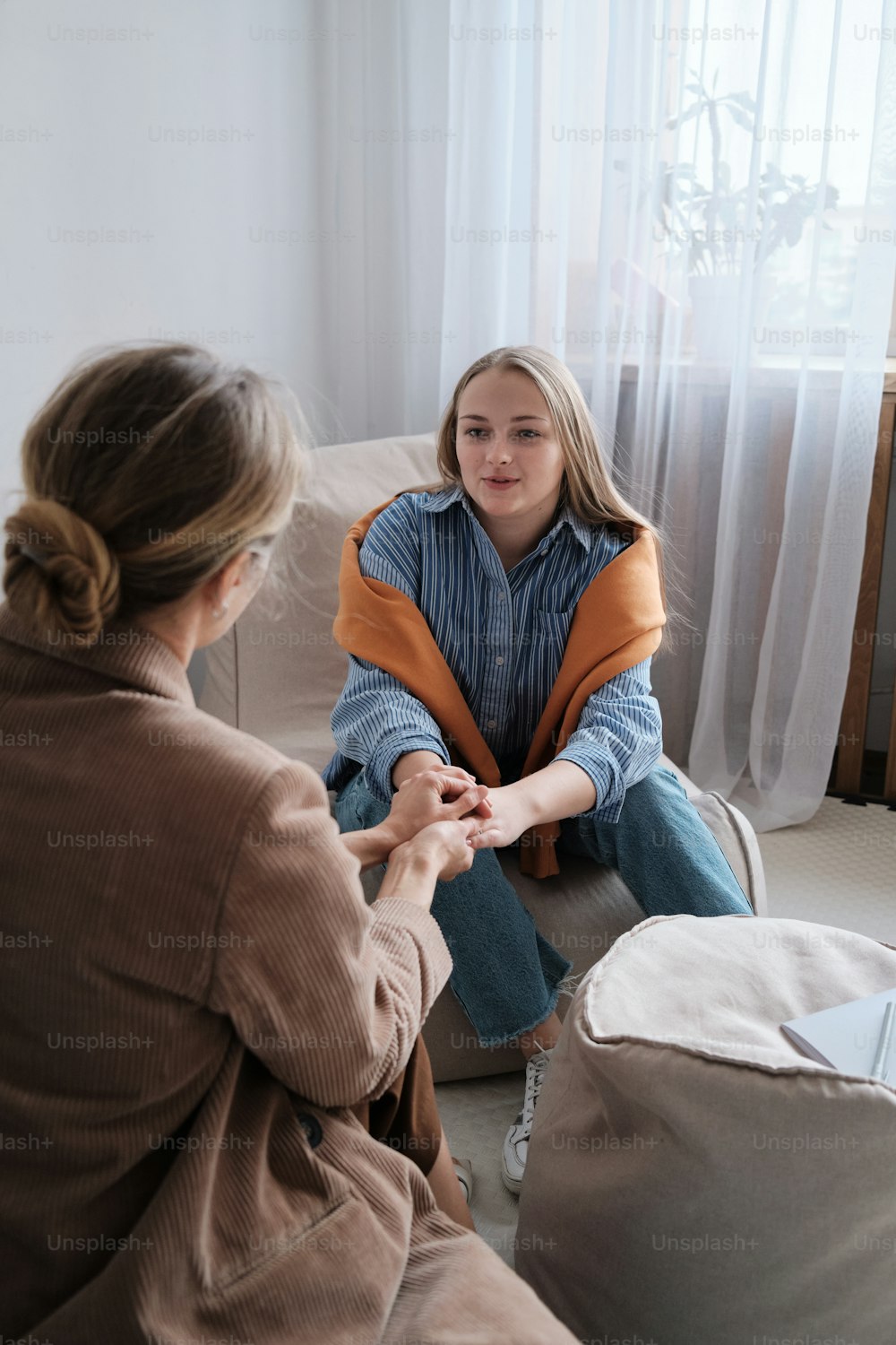 Una mujer sentada en un sofá hablando con otra mujer