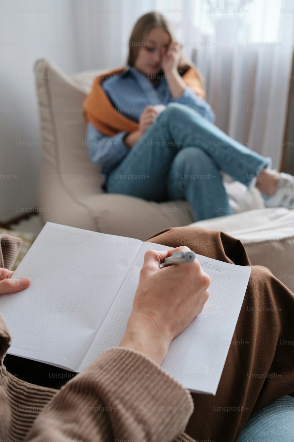 a woman sitting on a couch writing on a piece of paper