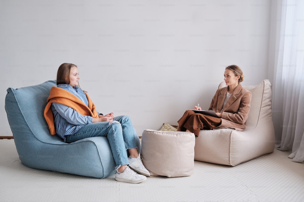 Dos mujeres sentadas en bolsas de frijoles en una habitación