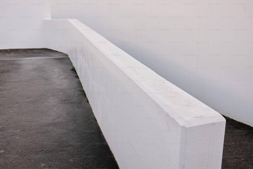 a white bench sitting next to a white wall