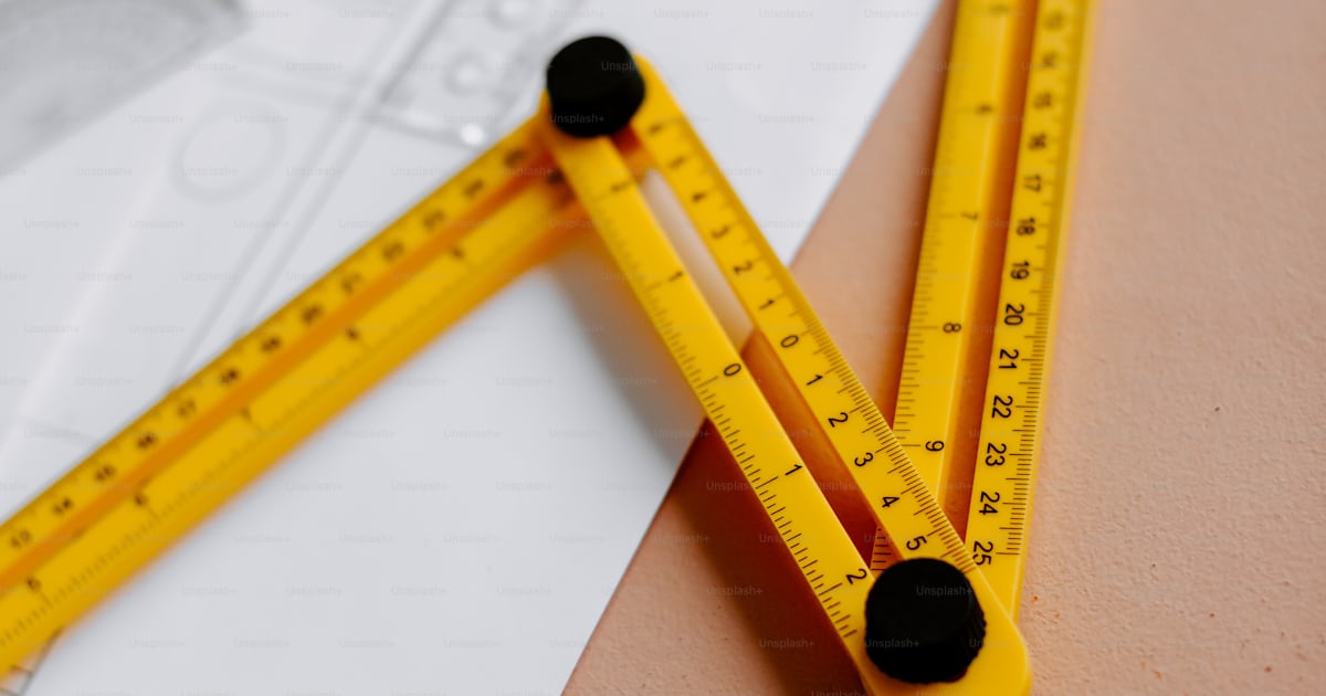 A pair of yellow rulers sitting on top of a piece of paper photo ...