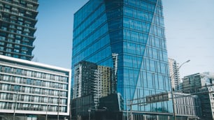 a very tall glass building next to other tall buildings