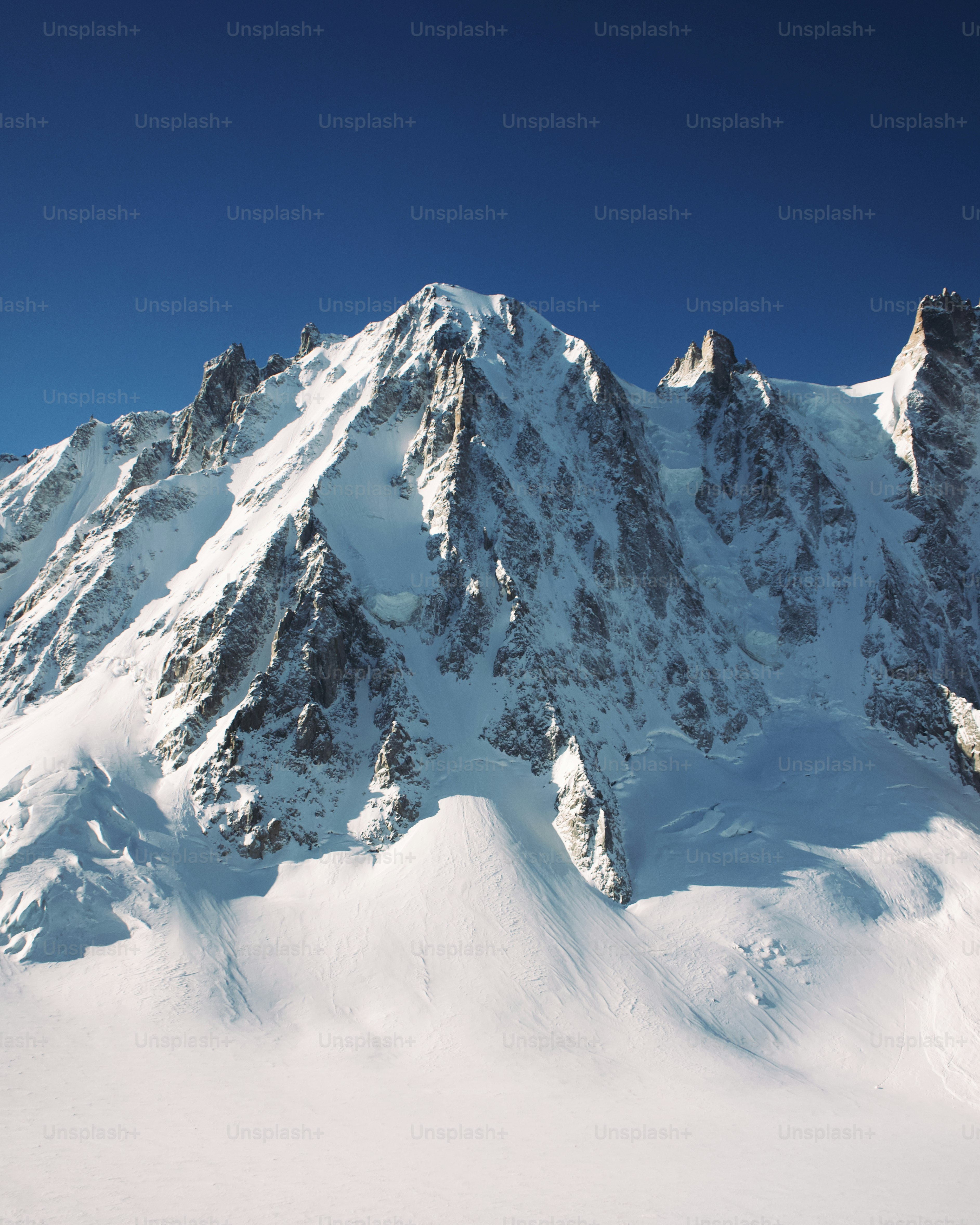 a large mountain covered in snow under a blue sky