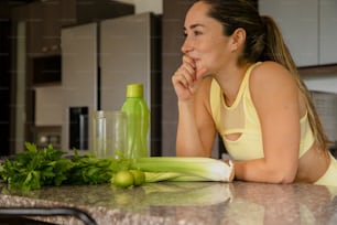 Une femme assise à un comptoir de cuisine avec des légumes