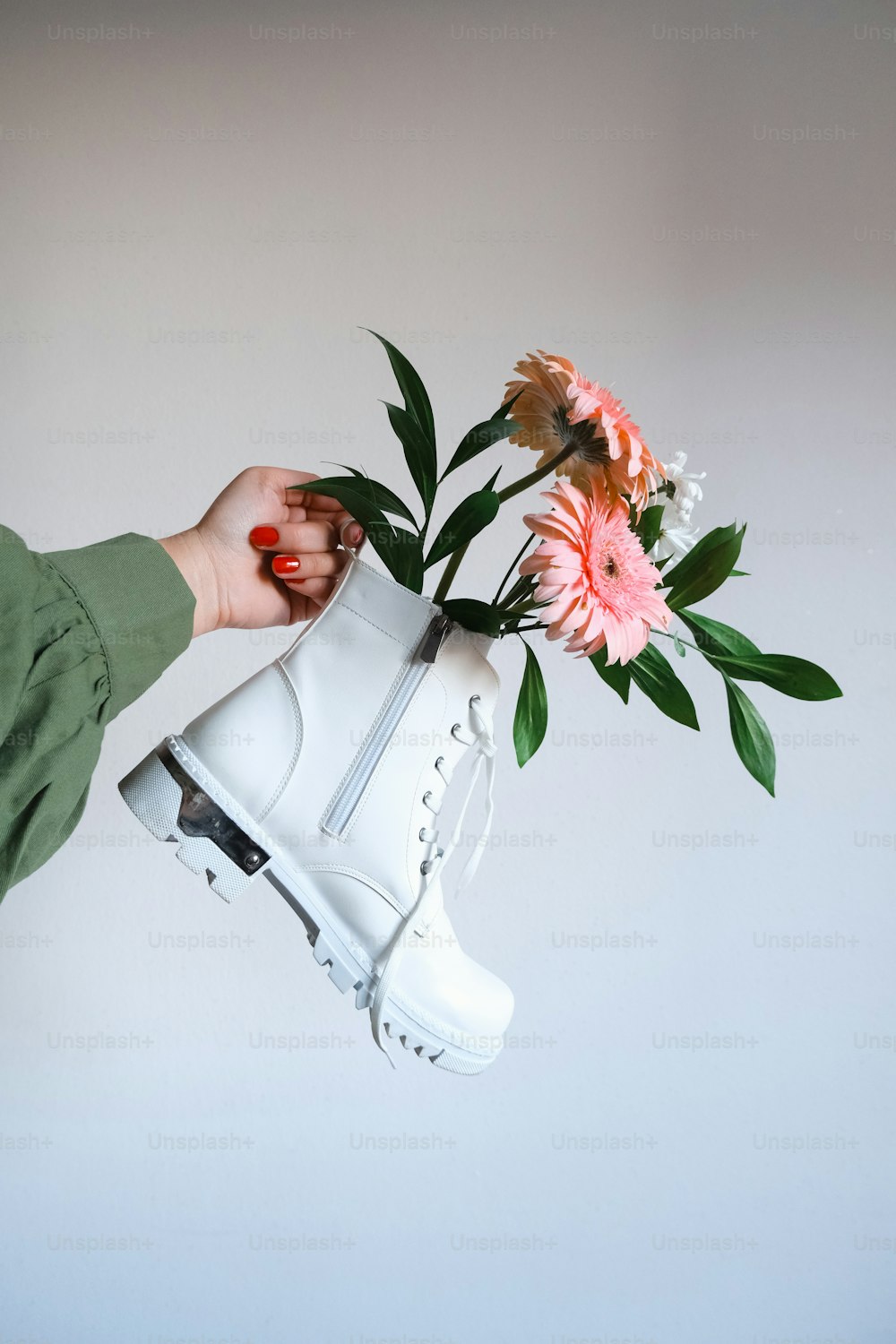 a person holding a white boot with flowers in it