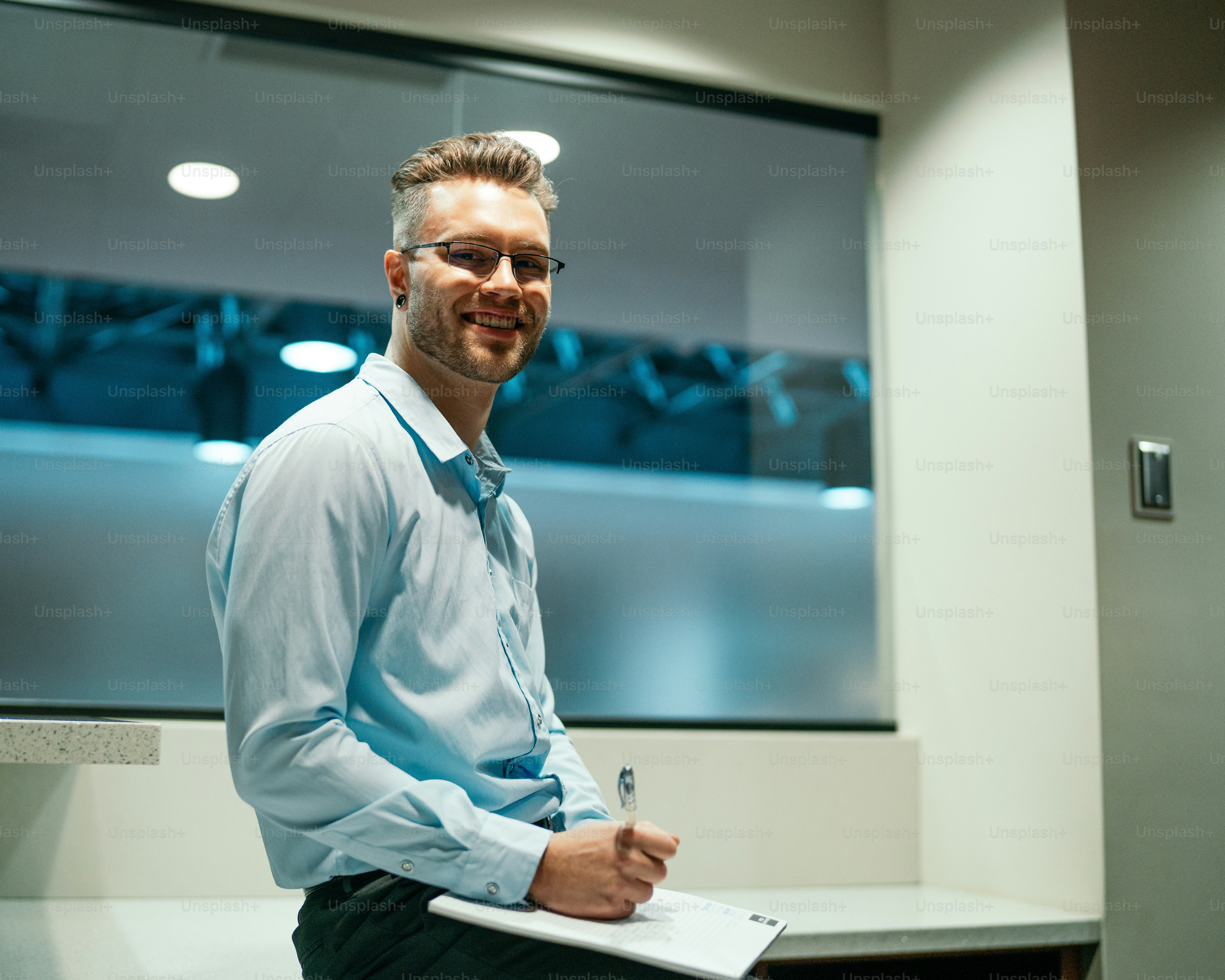 青いシャツを着た男がペンとノートを持っている