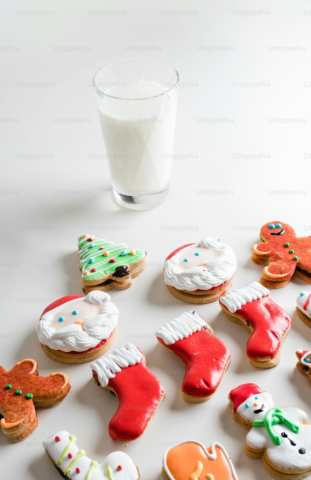 um copo de leite ao lado de um monte de biscoitos decorados