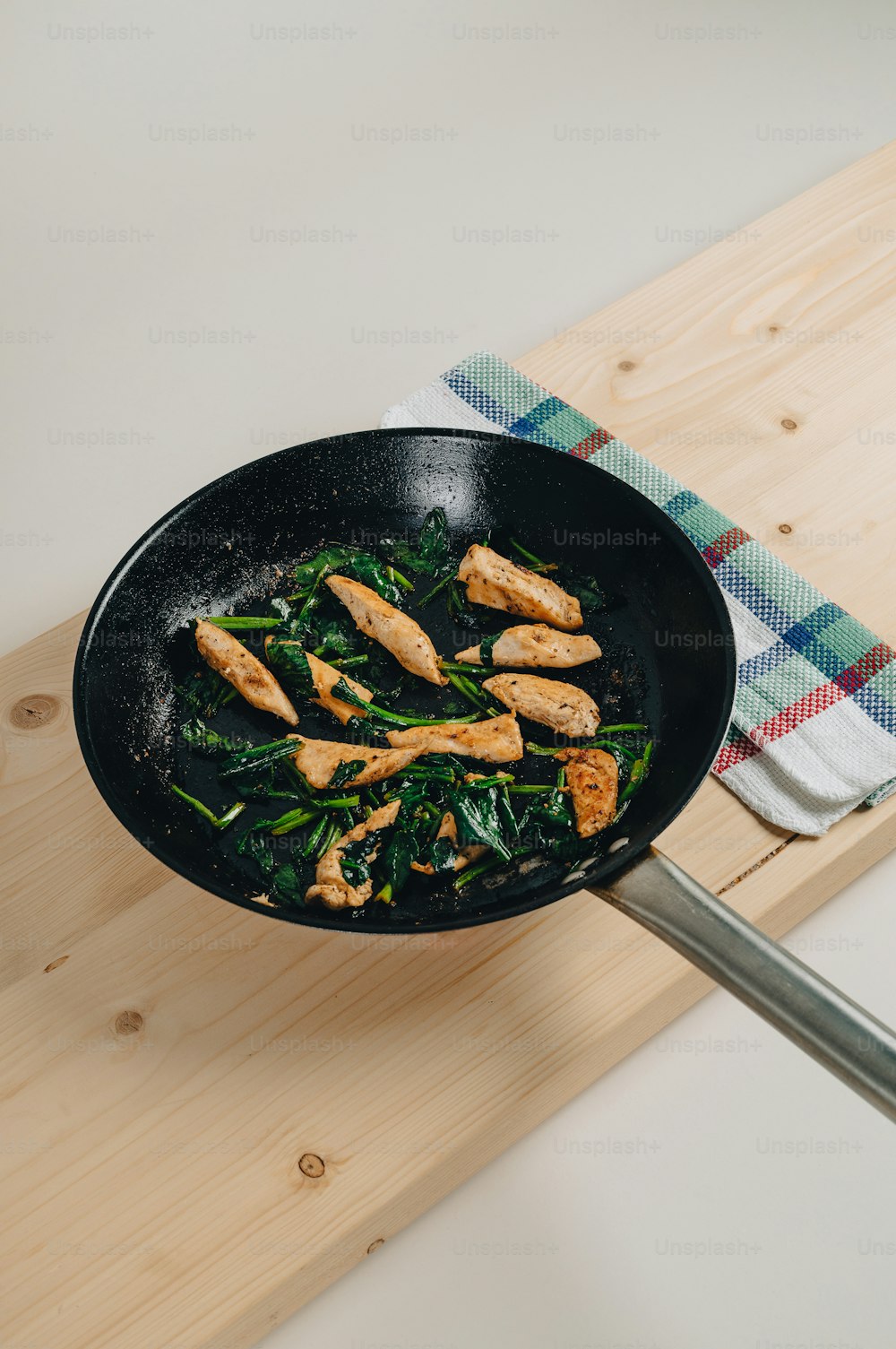 a skillet with chicken and spinach on a table