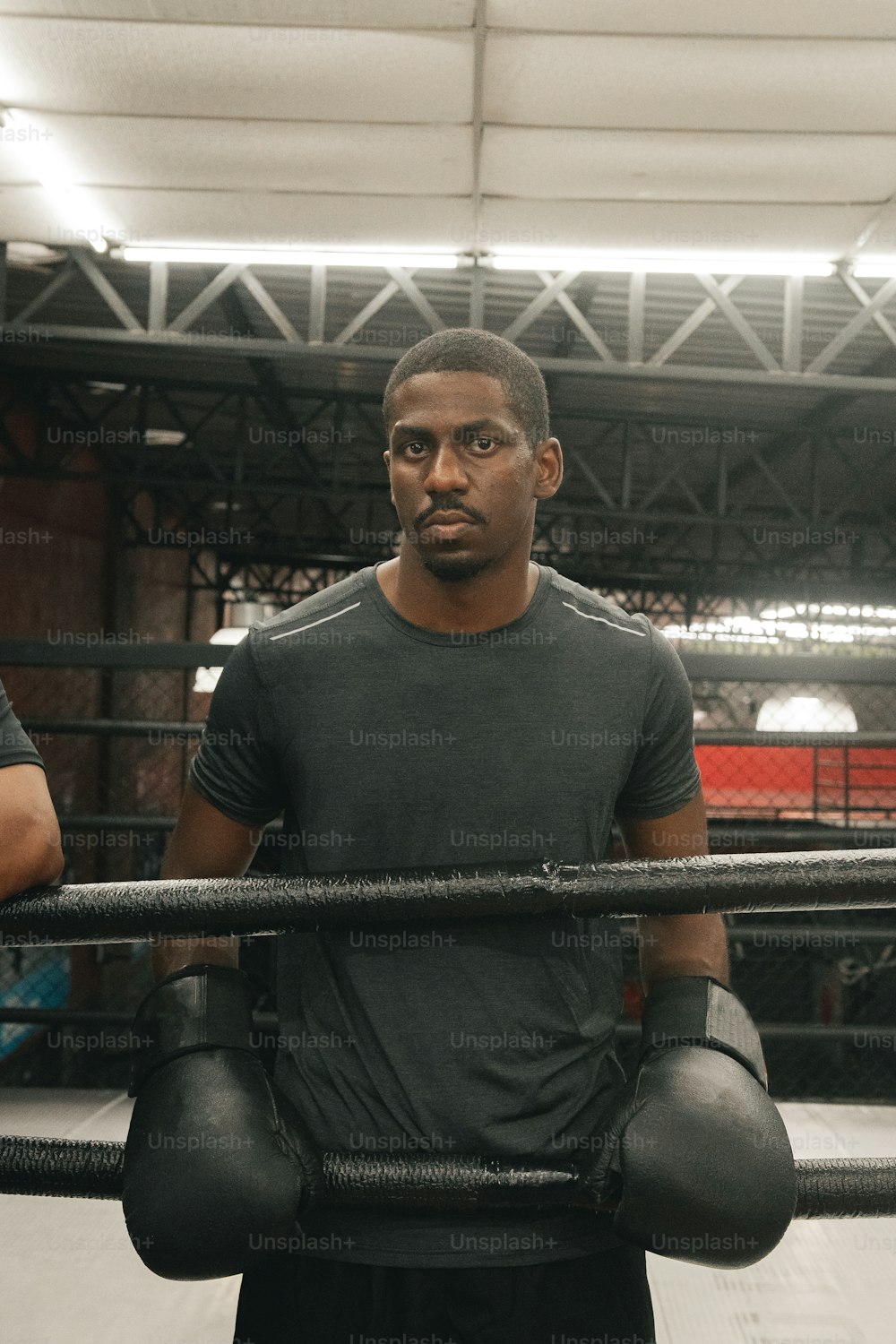 Un homme debout dans un ring de boxe tenant une paire de gants de boxe