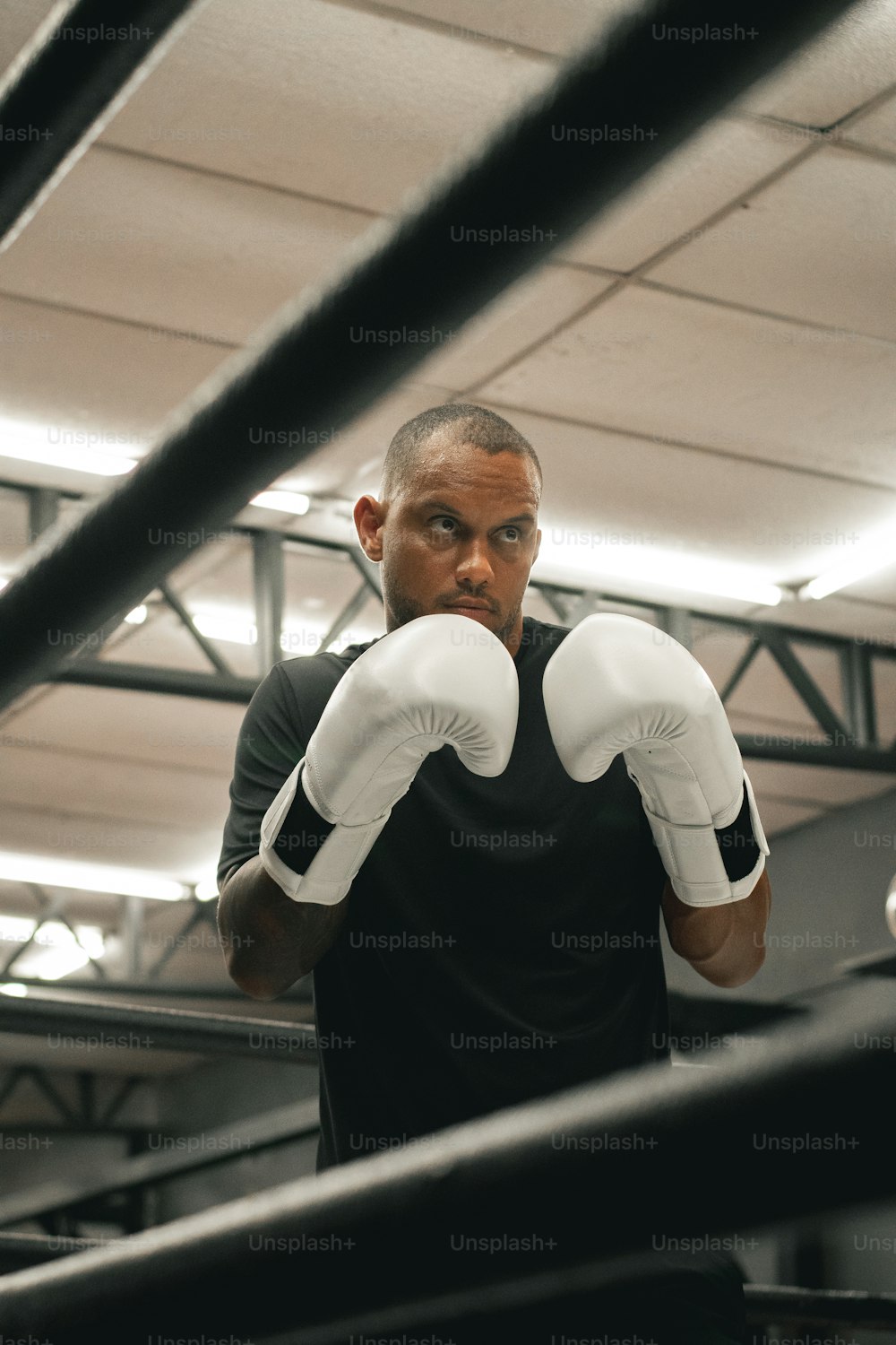 Ein Mann in schwarzem Hemd und weißen Boxhandschuhen