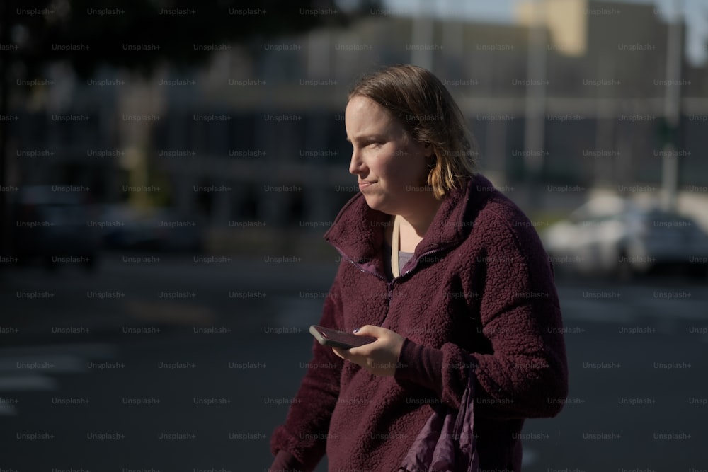 Una donna con una giacca marrone sta guardando il suo cellulare