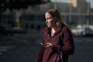 적갈색 재킷을 입은 여자가 휴대폰을 보고 있다