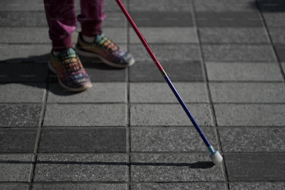 a person standing on a sidewalk with a cane