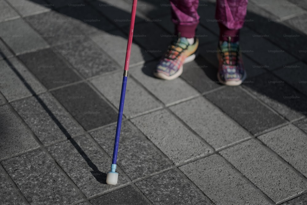 una persona in piedi su un marciapiede con un bastone da passeggio