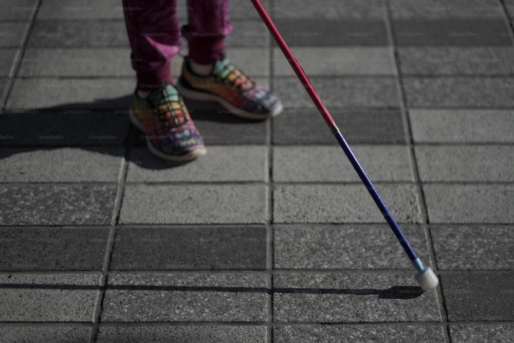 una persona in piedi su un marciapiede con un bastone